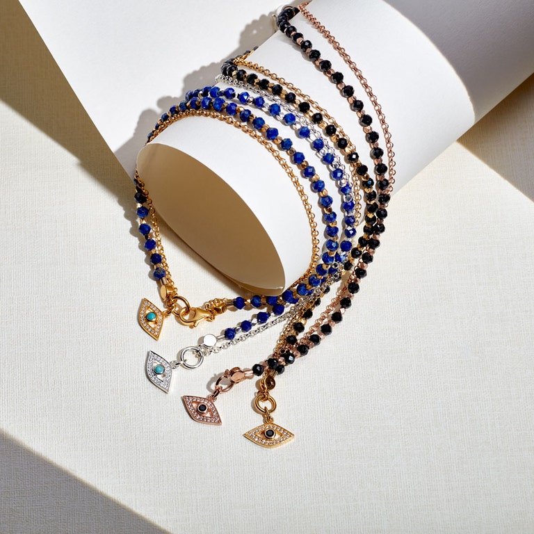 still life image of gold evil eye bracelet, silver evil eye bracelets and rose gold evil eye bracelets with gemstone beads