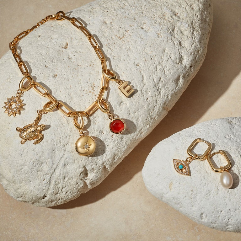 gold charm still life with gold chain bracelet and personalised charm