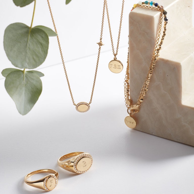 still life image of gold jewellery with engraved signet rings, engraved gold bracelets and engraved necklace