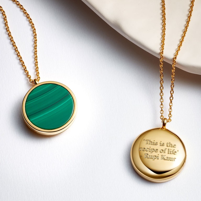 still life image of malachite photo locket and large gold locket necklace with engraving