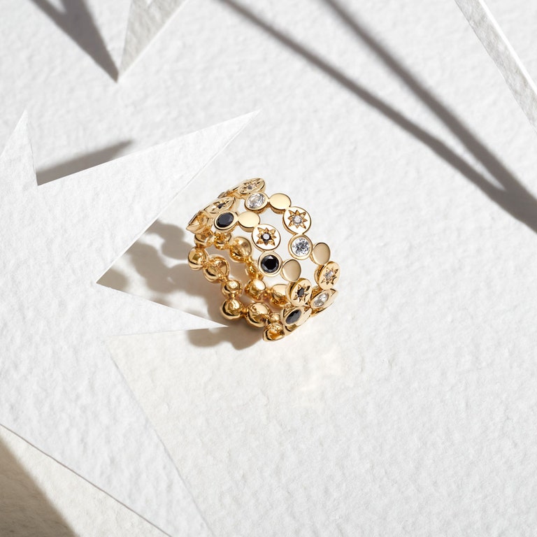 still life image of gold polaris rings with white sapphires and black spinel