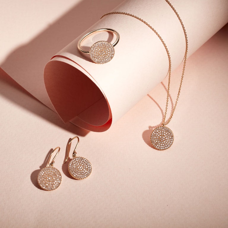 still life image of diamond drop earrings and diamond solid gold ring with diamond locket necklace