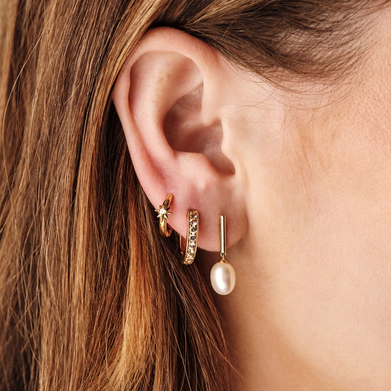 gold earring stack with sapphire huggie hoop earring and gold pearl drop earring
