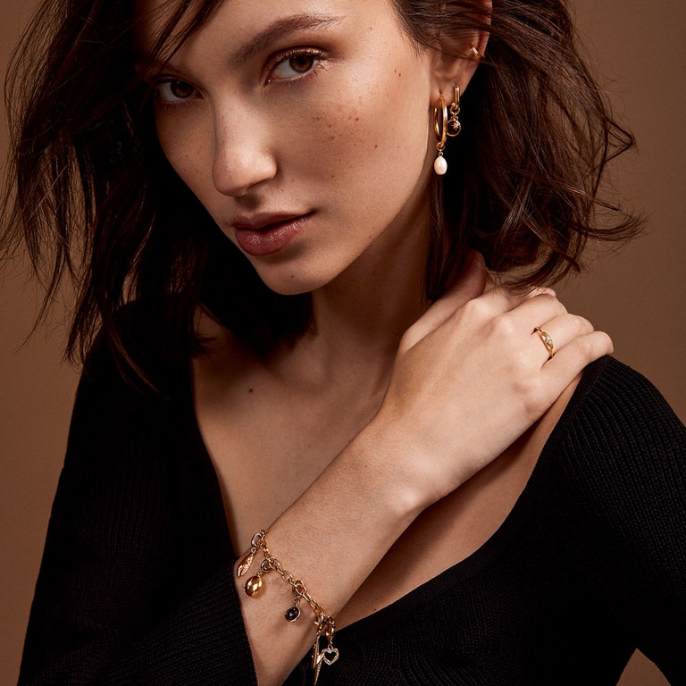 Model image of gold charm bracelet and charm earring stack